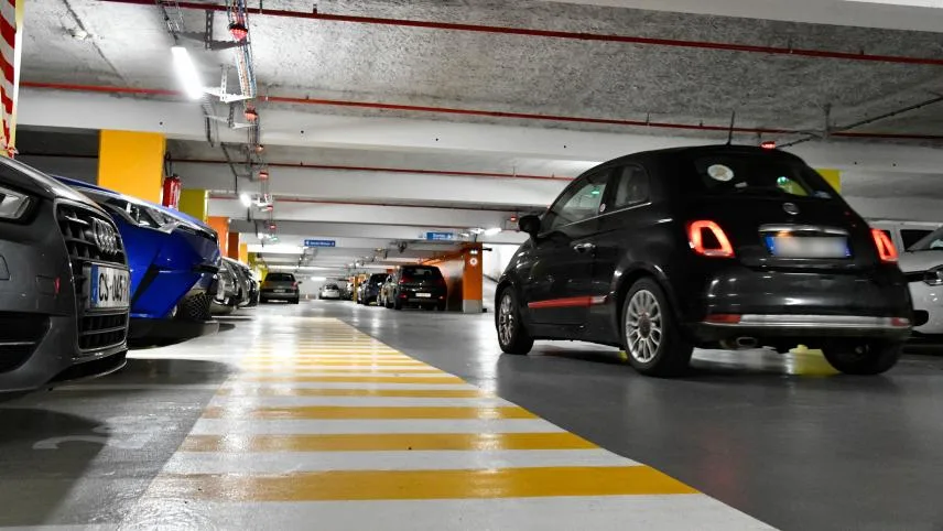 Allée d'un parking couvert avec marquages jaunes et voitures stationnées